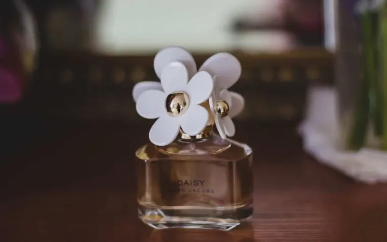 Frasco de perfume apoyado sobre una mesa de madera